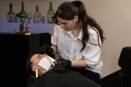Hair removal procedure in a barbershop. Nose hair wax removal.