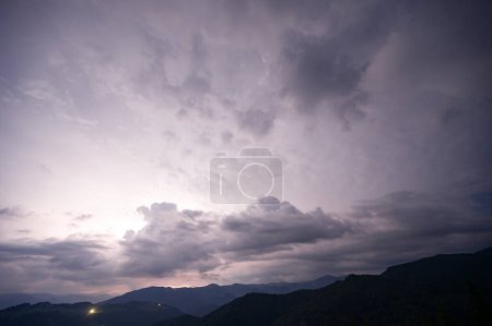 Ein abendliches Gewitter mit Blitz in den Karpaten, dem Dorf Dzembronya. Dramatische Wolken während eines Gewitters durchdringen das Licht des Blitzes in einer bergigen Region.