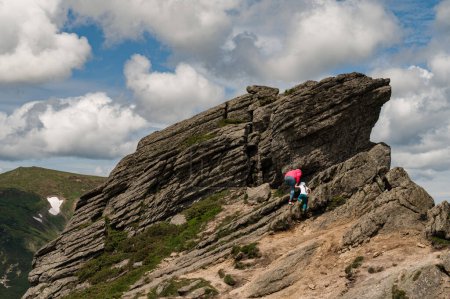 Madre e hija son escaladas en lo alto de una piedra rocosa ubicada en el Monte Ukhaty Kamin, una piedra de orejas en los Cárpatos.