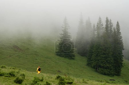 A tourist goes to the mountains in the rain and fog, unfavorable weather in the mountains for tourists.
