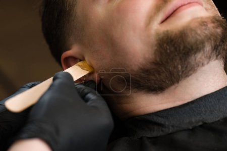 Ear hair wax removal. Hair removal procedure in a barbershop.
