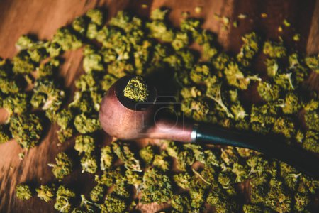 Holzpfeife zum Rauchen von Marihuana auf dem Tisch vor dem Hintergrund einer Knospe von cbd sativa oder indica tgk. Drogen und Medizin