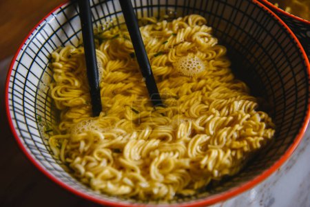 Instant pasta, Japanese and Chinese noodles. Ramen type soup in a plate with chopsticks, junk fast food. Quick-cooking pasta