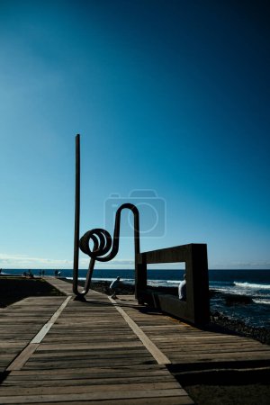 Foto de Playa de las Americas, Tenerife España. 18.12.2022 Stahl skulptur am Piscina Naturale sobre el fondo del mar y el cielo - Imagen libre de derechos