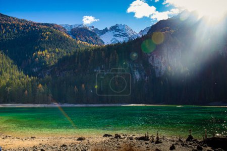 Foto de Las aguas cristalinas del lago Tovel, Trentino Alto Adigio, Italia. Vista de otoño con destello de sol. - Imagen libre de derechos