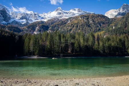 Foto de Las aguas cristalinas del lago Tovel, Trentino Alto Adigio, Italia. Vista panorámica con montañas nevadas en el fondo. - Imagen libre de derechos