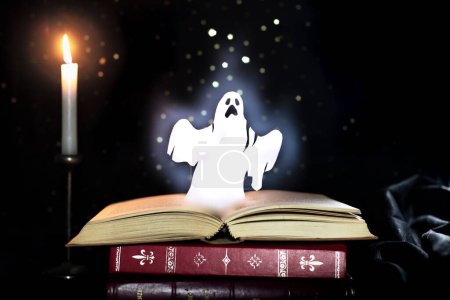 Leuchtende, leuchtende Geisterfigur, die in einem magischen Stillleben mit einer brennenden Kerze einem Buch entsteigt. Horror, gruselige Literatur, Gothic Stories.