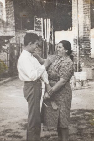 Téléchargez les photos : Mère et jeune fils plaisantent dans la cour de ta ferme. Italie 1960. Photographie d'archives noir et blanc. - en image libre de droit