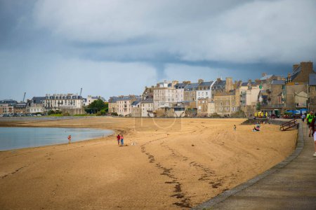 Foto de SAN MALO, FRANCIA - AGOSTO 2023 - Les bas Sablons paseo marítimo y playa en la pintoresca ciudad de Saint Malo, en un día lluvioso. Bretaña, Francia. - Imagen libre de derechos