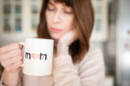 Photo for Caucasian woman, tired or thoughtful, holding a mother's  day cup of coffee. charge of parenting concept. - Royalty Free Image