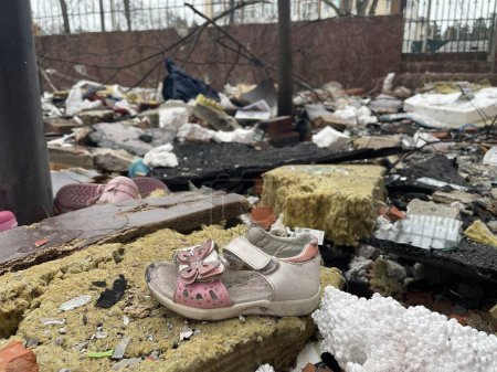Téléchargez les photos : Des chaussures pour enfants qui sont sorties de maisons détruites par un missile russe. Guerre en Ukraine. Concept de destruction. - en image libre de droit