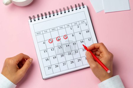 Foto de El concepto del ciclo menstrual, punto. La mujer marca los días en el calendario. - Imagen libre de derechos