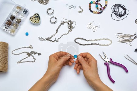 The designer makes handmade jewelry at the workplace.