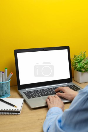 Téléchargez les photos : Une femme utilise un ordinateur portable avec un écran blanc vierge sur le bureau. - en image libre de droit
