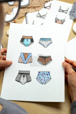 Téléchargez les photos : La créatrice dessine des croquis de sous-vêtements féminins. Lingerie culotte et soutien-gorge sur papier. - en image libre de droit