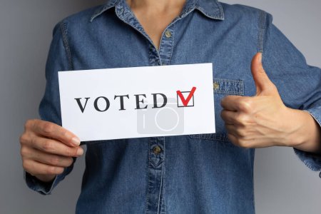 Téléchargez les photos : Pouce en l'air et feuille de vote dans la main de la femme. Concept électoral. - en image libre de droit