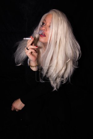 Foto de Retrato de una hermosa mujer rubia con ojos verdes fumando un cigarrillo - Imagen libre de derechos