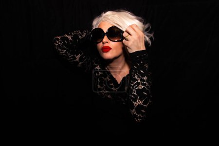 Foto de Hermosa mujer rubia con gafas de sol sobre un fondo negro - Imagen libre de derechos