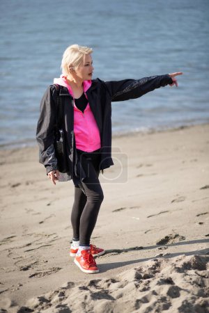Foto de Atractiva mujer en la playa señalando con el dedo - Imagen libre de derechos