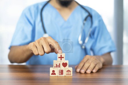 Foto de Médico mano la organización de bloques de madera apilamiento con icono médico, seguro para su concepto de salud - Imagen libre de derechos