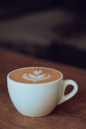 Téléchargez les photos : Tasse à café sur table en bois. Concept de Latte Art. Café au lait dans une tasse blanche. Papier peint vertical café. Table de petit déjeuner. Barista habileté à faire du café art. Boissons du matin. Cappuccino en tasse blanche. - en image libre de droit