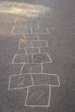 Chalk drawings on asphalt. Hopscotch game concept. Childhood concept. Painted numbers on the road. Outdoor games. Children activity. Outdoor playground in the city. Colourful hopscotch line.