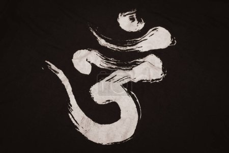 Om word on dark background. Spiritual sign isolated. Sacred Om symbol printed on clothes. Sanskrit magic word. Indian calligraphy on printed fabric. Om mantra. Powerful religious symbol.