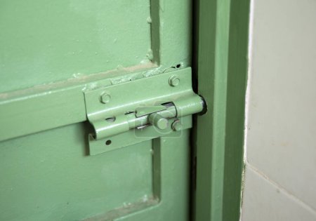 Die eiserne grüne Tür wird am Riegel von innen geschlossen, der Riegel aus nächster Nähe entfernt, alt zur Sicherheit