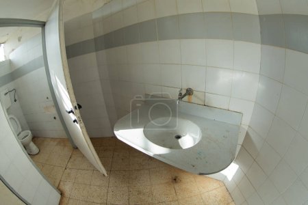 weiße Toilette auf schmutziggelben Fliesen, verlassene Stelle, keine Reinigung, ungepflegte Toilette