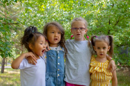 Téléchargez les photos : Groupe souriant d'enfants dans le parc, parlant entre eux - en image libre de droit