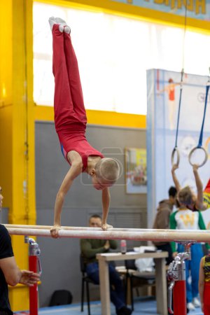 Foto de Gymnast exercise parallel bars in championship gymnastics, boy handstanding on bars - Imagen libre de derechos