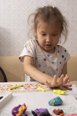 Foto de Una niña pequeña creando juguetes de plastilina. Foto vertical - Imagen libre de derechos