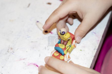 Photo for Child making colorful clay person on white table, closeup - Royalty Free Image