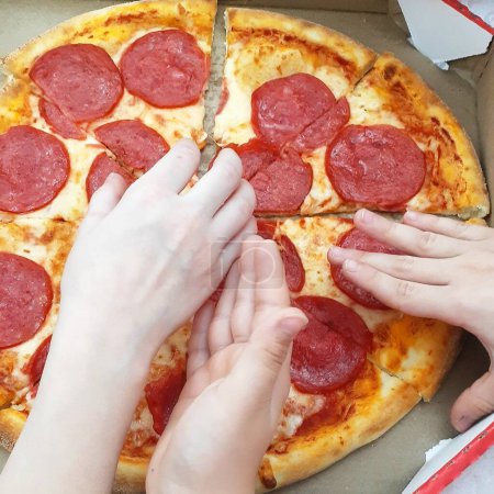 Foto de Familia comiendo pizza. Niños sosteniendo una rebanada de pizza. - Imagen libre de derechos