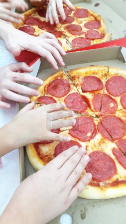 Photo for Children taking slice of peperoni pizza. Top view - Royalty Free Image
