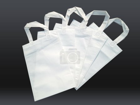 Foto de White color non woven bags on black background. Reduce reuse recycle Bags. Few ECO friendly fabric bags. - Imagen libre de derechos