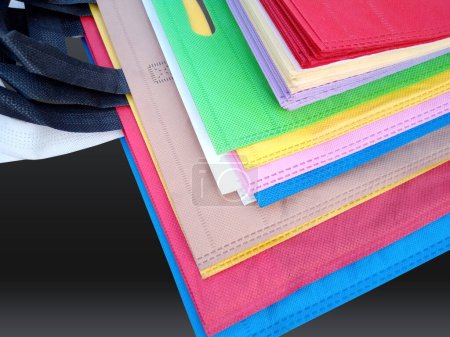 Foto de Colorful non woven bags on black background. Reduce reuse recycle Bags. Few ECO friendly fabric bags. - Imagen libre de derechos