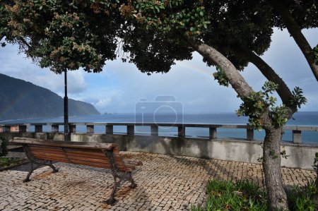 Foto de Empty bench at Atlantic Ocean coast, Rainbow over ocean, Madeira island - Imagen libre de derechos
