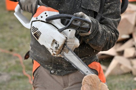Mann schneidet Holz mit Kettensäge