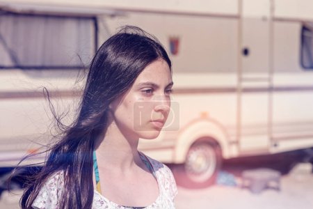 Téléchargez les photos : Portrait d'une belle adolescente debout devant un camping-car, vent soufflant ses cheveux, photo vintage filtrée rétro, look hippie - en image libre de droit