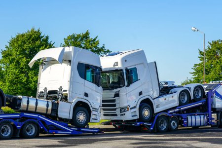 Foto de Transporte de camiones nuevos en remolques de camiones especializados, entrega a distribuidores, fondo azul cielo - Imagen libre de derechos