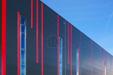 Fachada de paneles sándwich coloridos de diseño moderno con rayas verticales rojas de un nuevo edificio industrial con aislamiento térmico de construcción metálica