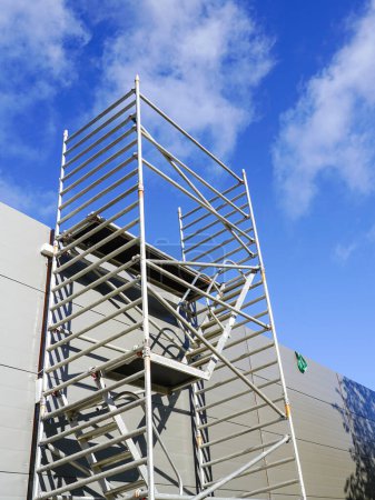 Photo for Modern metal tubular multilevel scaffolding next to the sandwich panel facade of a new building - Royalty Free Image