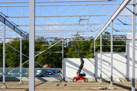 Photo for New building steel framework assembly using self propelled lift platform, unfinished warehouse building - Royalty Free Image