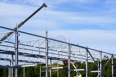 Photo for New building steel framework assembly using telescopic boom crane and self propelled lift platform, unfinished warehouse building - Royalty Free Image