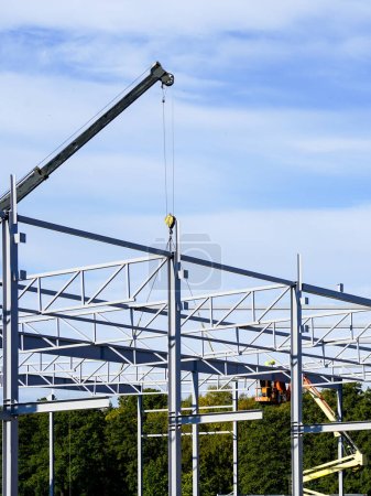 New building steel framework assembly using telescopic boom crane and self propelled lift platform, unfinished warehouse building
