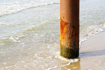 Téléchargez les photos : A vertical thick rusty metal pole on the seashore rusted by salty sea water, corrosion process - en image libre de droit
