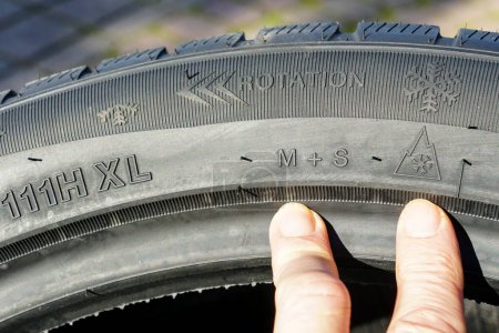 Foto de Markings on the sidewall of a new winter tire, markings for speed, load, rotation direction, mud, snow, snowflake symbol and winter tire mark - Imagen libre de derechos