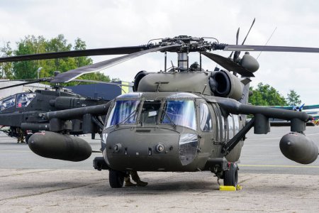 Foto de Liepaja, Latvia - August 7, 2022: US Army Sikorsky UH-60 Black Hawk and Apache AH-64D military helicopters after landing at the airport, front view - Imagen libre de derechos