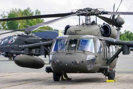 Téléchargez les photos : Liepaja, Latvia - August 7, 2022: US Army Sikorsky UH-60 Black Hawk and Apache AH-64D military helicopters after landing at the airport, front view - en image libre de droit
